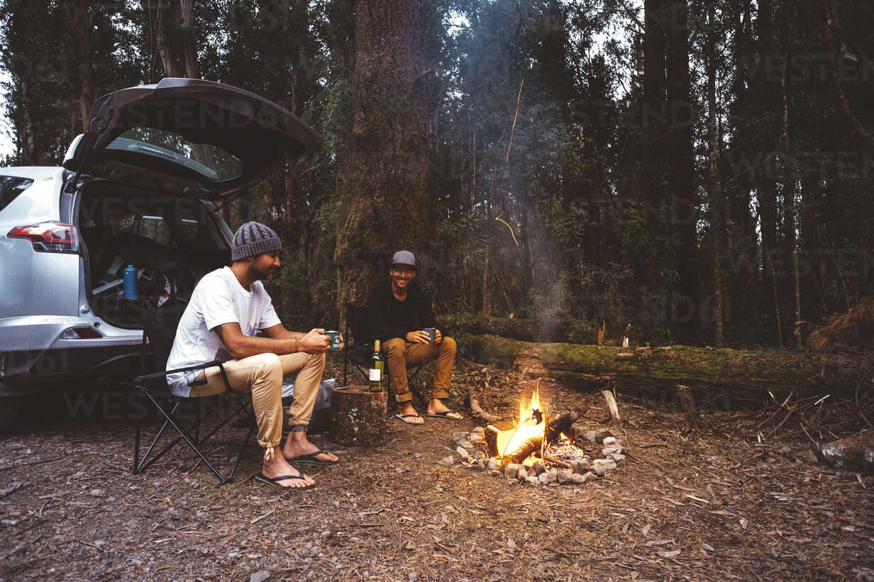 Friends relaxing by a campfire in the forest during a camping trip – LITEGUEST outdoor lifestyle